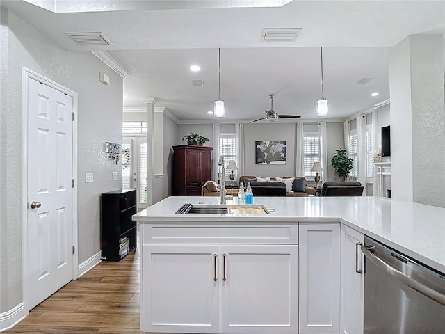 kitchen featuring stainless steel dishwasher, a sink, visible vents, a textured wall, and wood finished floors