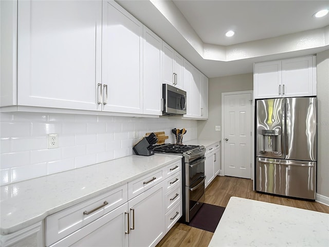 kitchen featuring dark wood finished floors, white cabinets, stainless steel appliances, and decorative backsplash