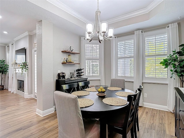 dining space featuring baseboards, light wood-type flooring, a chandelier, and crown molding