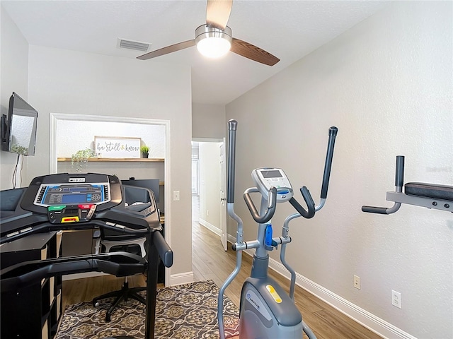 workout area with baseboards, visible vents, wood finished floors, and a ceiling fan