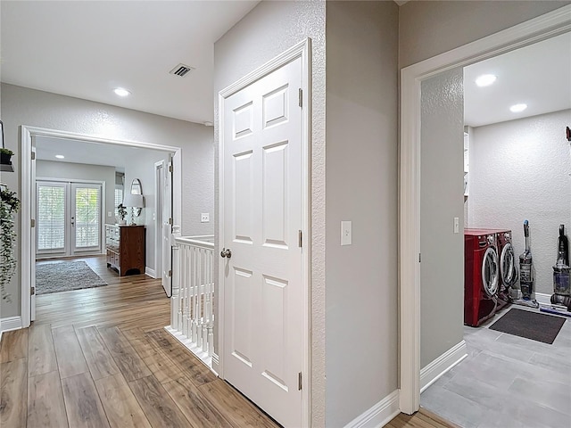 hallway featuring baseboards, visible vents, washer and dryer, and a textured wall