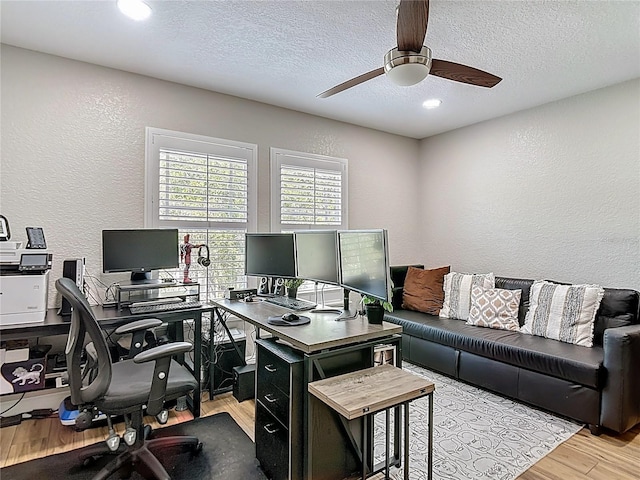 office area with a textured ceiling, a ceiling fan, a textured wall, and wood finished floors