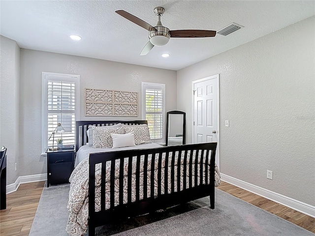 bedroom featuring visible vents, wood finished floors, and a textured wall