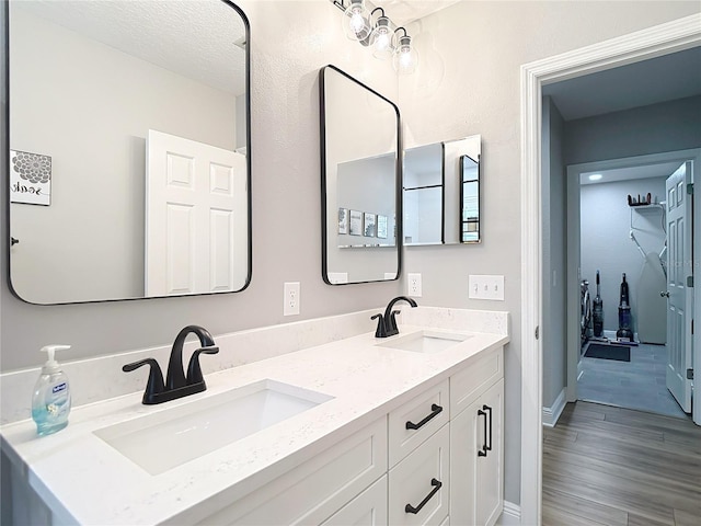 bathroom featuring double vanity, a sink, wood finished floors, and baseboards