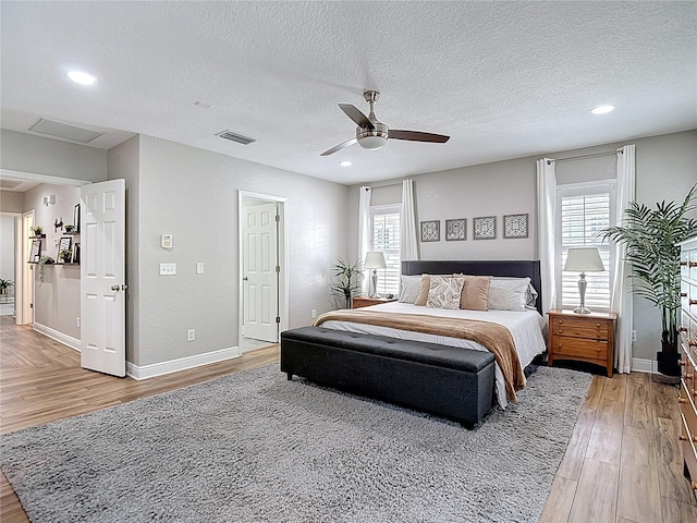 bedroom featuring a textured ceiling, multiple windows, and light wood finished floors