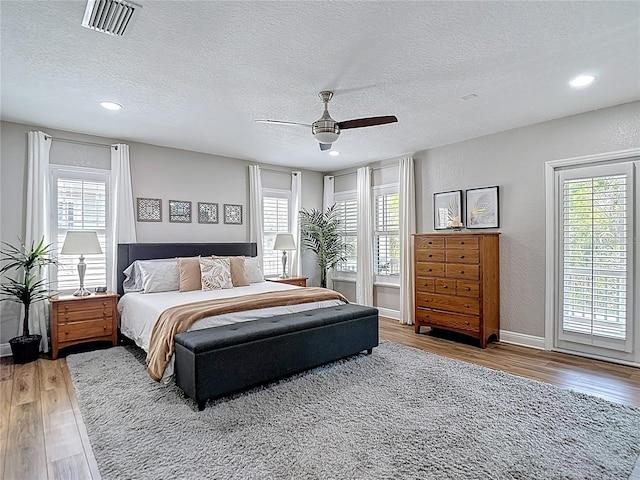 bedroom with visible vents, wood finished floors, and multiple windows