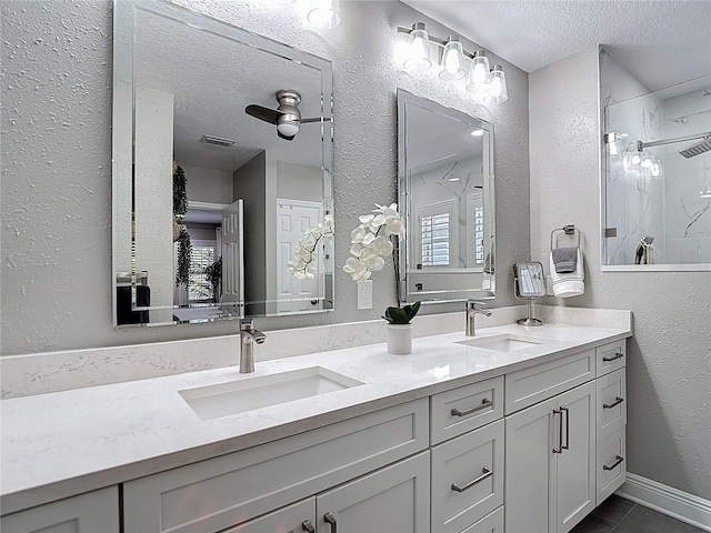 full bath with a marble finish shower, a textured ceiling, a sink, and double vanity