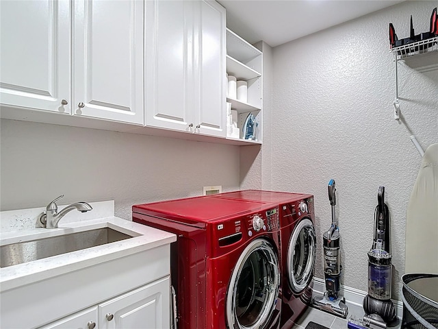 laundry room with a sink, washing machine and dryer, cabinet space, and a textured wall