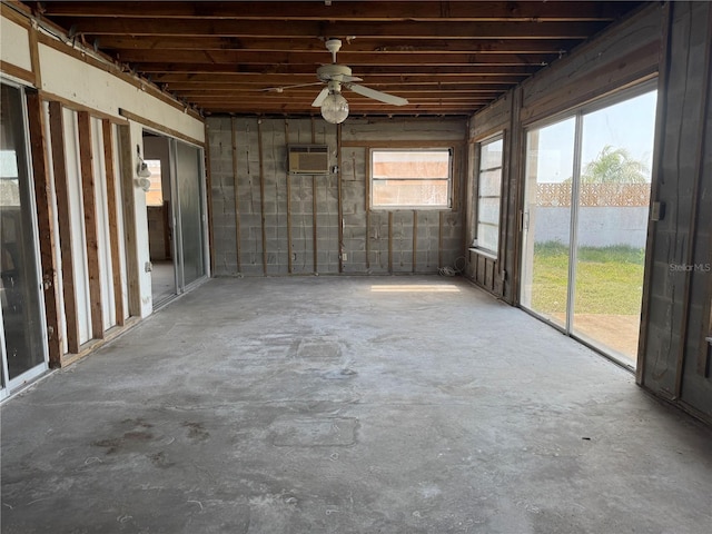 unfurnished sunroom with ceiling fan and a wall unit AC
