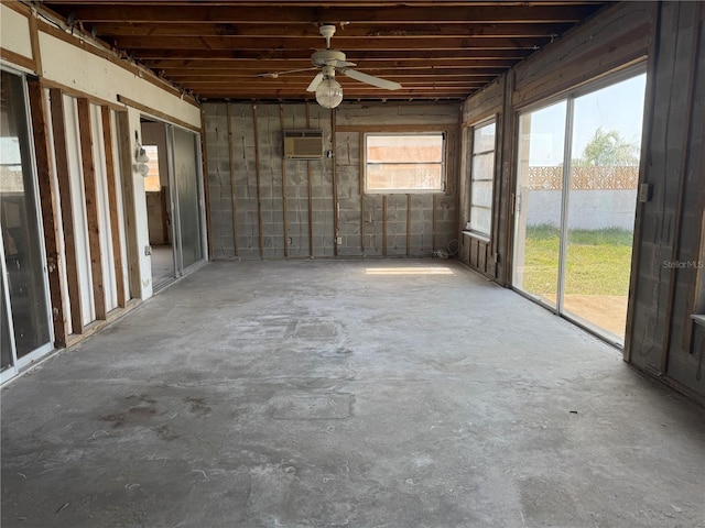unfurnished sunroom with a wall mounted air conditioner and ceiling fan