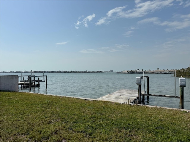 view of dock featuring a lawn and a water view