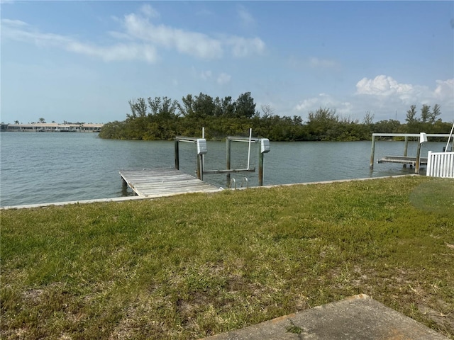 dock area with boat lift, a water view, and a yard
