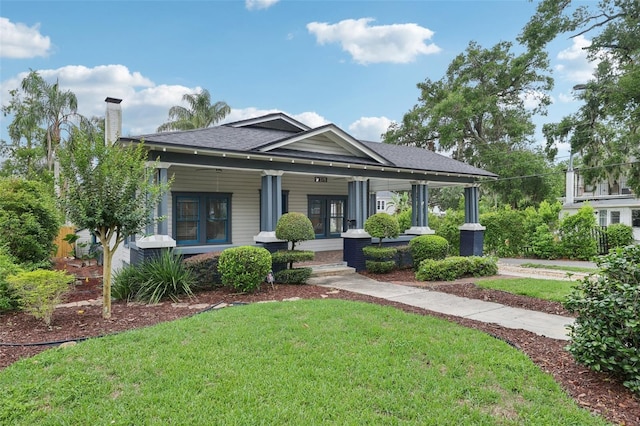 515 Frank Lloyd Wright Way, Lakeland, FL 33803 - view of front of house featuring a front yard, a porch, a chimney, and roof with shingles