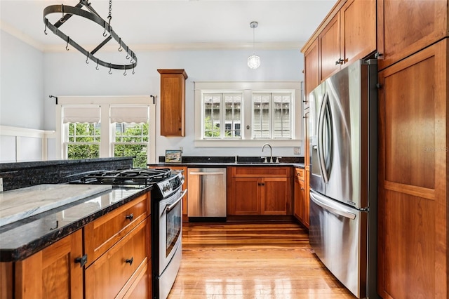 515 Frank Lloyd Wright Way, Lakeland, FL 33803 - kitchen with stainless steel appliances, a sink, crown molding, brown cabinets, and light wood-style flooring