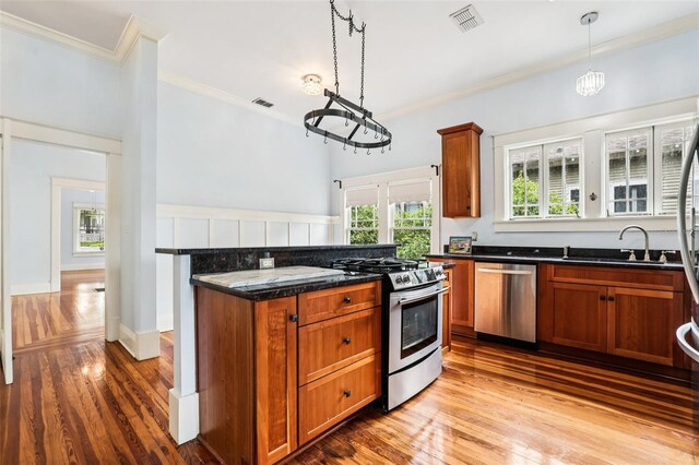 515 Frank Lloyd Wright Way, Lakeland, FL 33803 - kitchen featuring appliances with stainless steel finishes, crown molding, brown cabinetry, and light wood finished floors