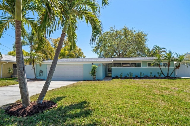 view of front of property with fence, an attached garage, concrete driveway, a front lawn, and stucco siding
