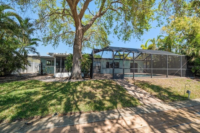 back of house with a lawn, an outdoor pool, and glass enclosure
