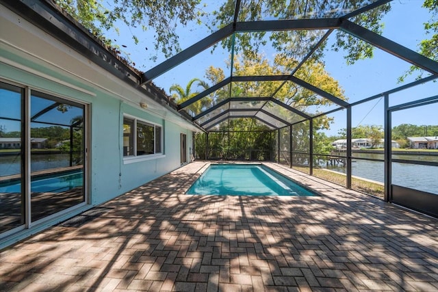 pool featuring glass enclosure, a water view, and a patio area