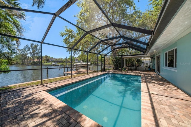 pool with glass enclosure, a water view, and a patio area
