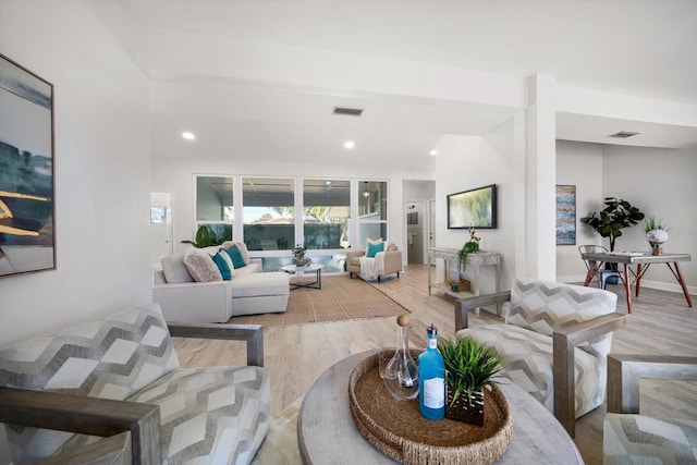 living room with lofted ceiling, recessed lighting, baseboards, light wood finished floors, and visible vents
