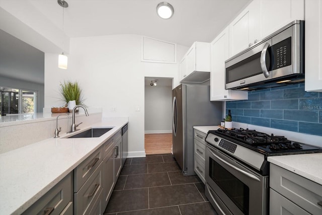kitchen featuring tasteful backsplash, stainless steel appliances, dark tile patterned floors, a sink, and white cabinets
