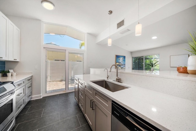 kitchen featuring a sink, hanging light fixtures, dark tile patterned floors, stainless steel appliances, and visible vents