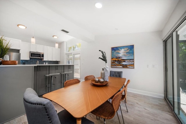 dining area featuring lofted ceiling with beams, baseboards, a wealth of natural light, and visible vents