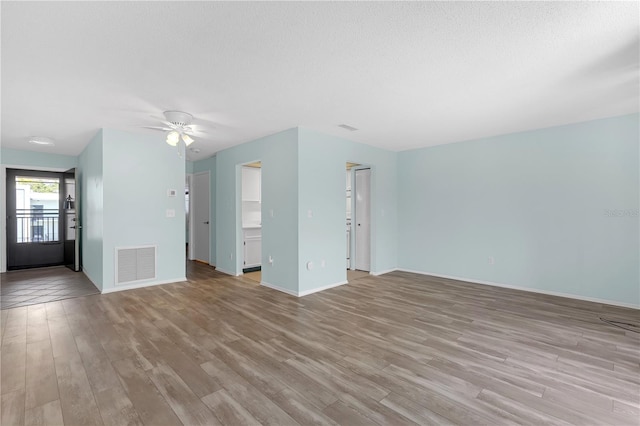 unfurnished living room featuring visible vents, a ceiling fan, light wood-style flooring, and baseboards