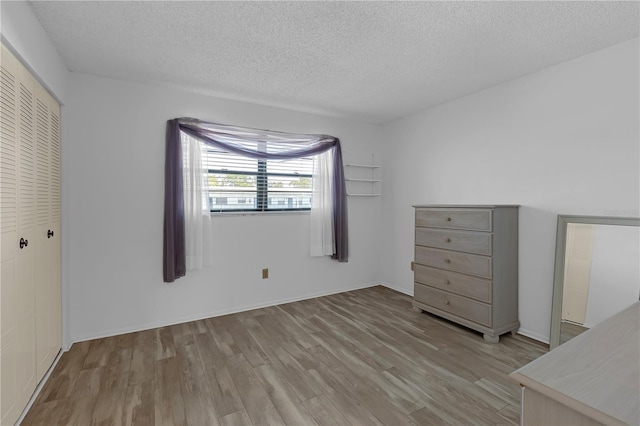 unfurnished bedroom with a textured ceiling, a closet, and wood finished floors