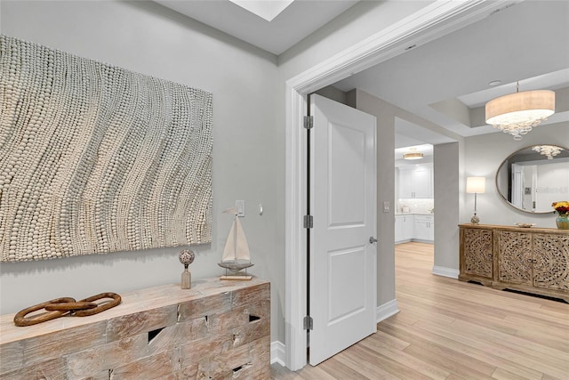 hallway featuring light wood-type flooring and baseboards