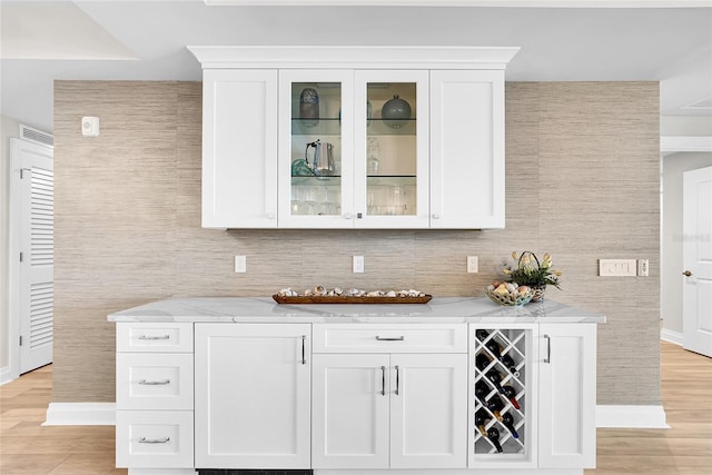 bar featuring baseboards, tasteful backsplash, and light wood finished floors