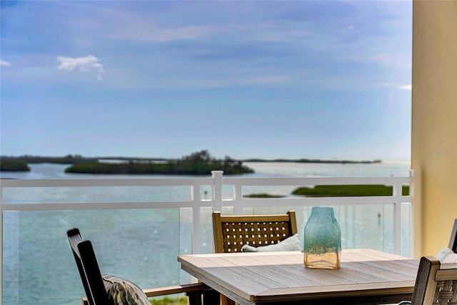 balcony with outdoor dining space and a water view