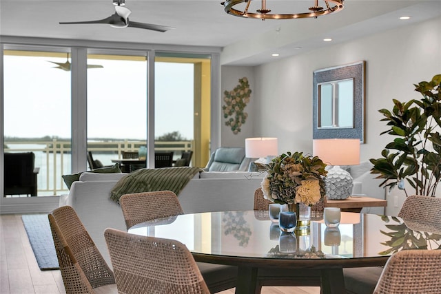 dining space featuring ceiling fan with notable chandelier, a wall of windows, wood finished floors, and recessed lighting