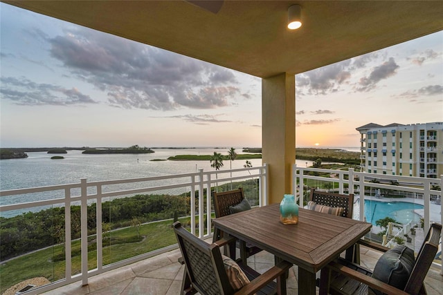 balcony with a water view and outdoor dining space