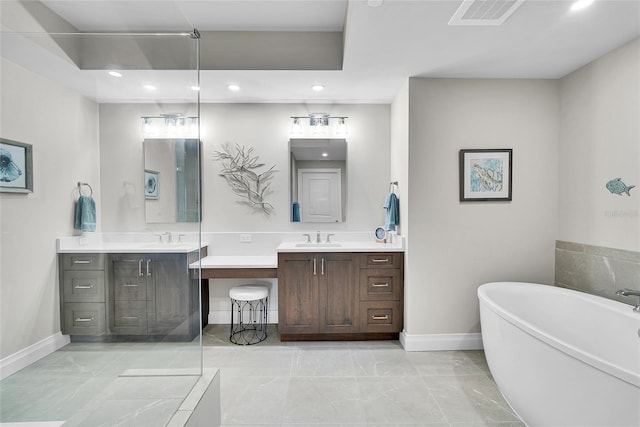 bathroom with baseboards, a freestanding tub, and two vanities
