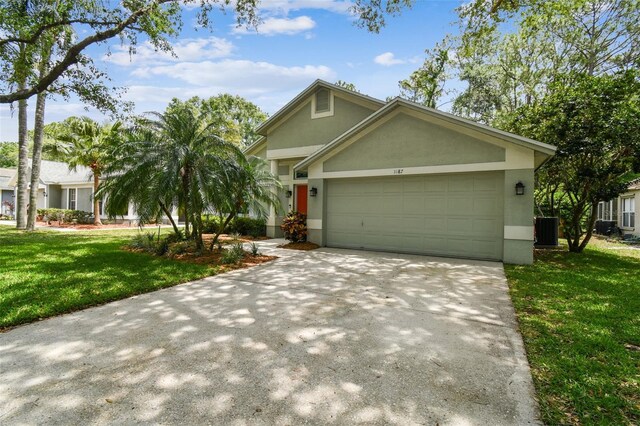 1187 Mistwood Dr, Tarpon Springs, FL 34688 - view of front of home with cooling unit, concrete driveway, a garage, a front yard, and stucco siding
