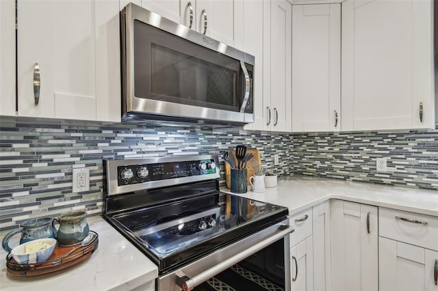 1187 Mistwood Dr, Tarpon Springs, FL 34688 - kitchen with stainless steel appliances, decorative backsplash, and white cabinetry