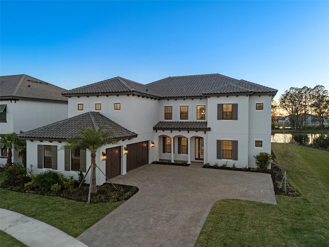 33736 Ocean Spray Ln, Wesley Chapel, FL 33543 - mediterranean / spanish-style home featuring a tile roof, decorative driveway, stucco siding, and a front lawn