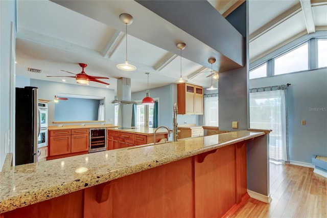 kitchen with ceiling fan, beam ceiling, island range hood, light wood-type flooring, and beverage cooler