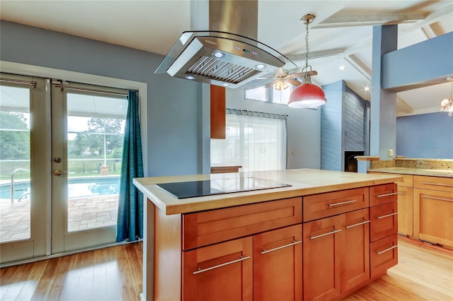 kitchen with black electric cooktop, island range hood, a ceiling fan, and a wealth of natural light