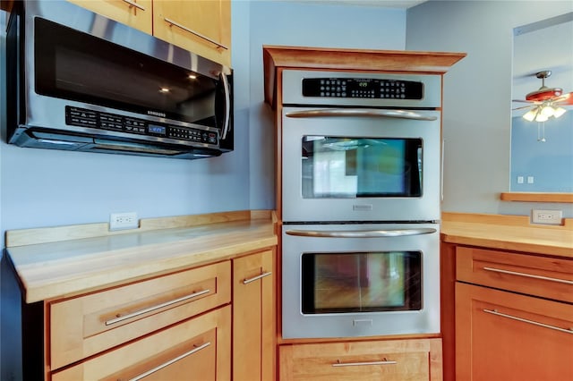 kitchen with wood counters, a ceiling fan, and stainless steel appliances