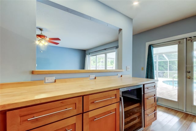 kitchen with wood counters, ceiling fan, wine cooler, light wood-style floors, and brown cabinetry