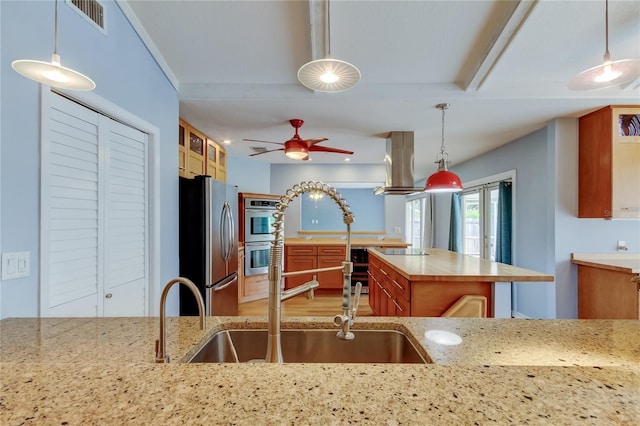 kitchen featuring visible vents, stainless steel appliances, a ceiling fan, island range hood, and light stone counters