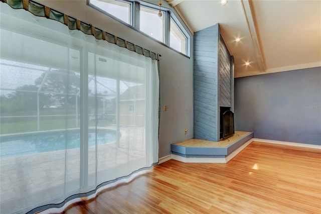 bathroom with baseboards, lofted ceiling, a fireplace, and wood finished floors