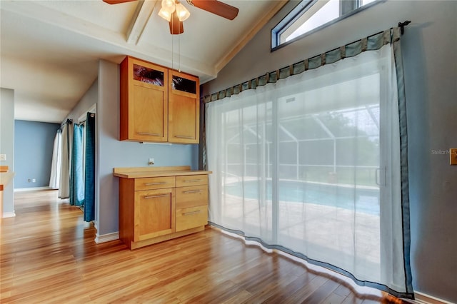 kitchen with light countertops, baseboards, a ceiling fan, lofted ceiling, and light wood-type flooring