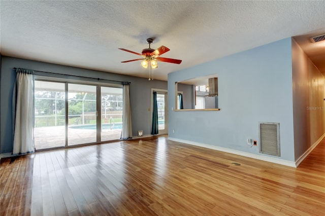 unfurnished room with baseboards, visible vents, wood finished floors, and a ceiling fan