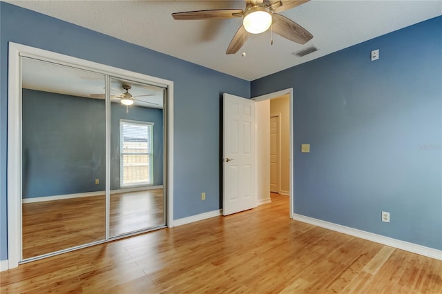 unfurnished bedroom featuring light wood-type flooring, baseboards, ceiling fan, visible vents, and a closet