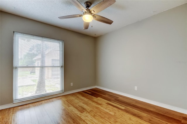 empty room with a ceiling fan, baseboards, and light wood-style floors
