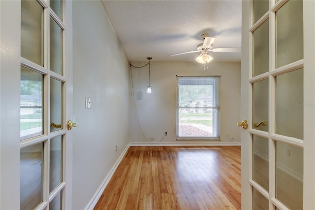 unfurnished room with baseboards, light wood-type flooring, ceiling fan, and a textured ceiling