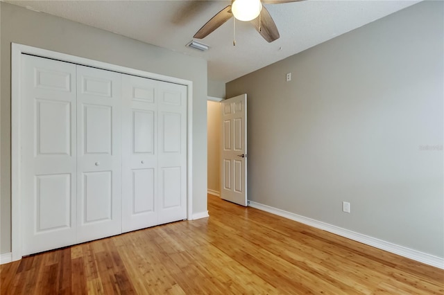 unfurnished bedroom with baseboards, light wood finished floors, visible vents, a ceiling fan, and a closet